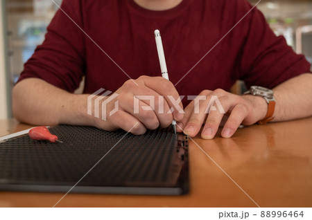 A man uses a special stylus to write a letter in braille.  88996464
