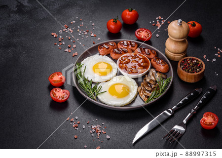 Full english breakfast with bean, fried eggs, roasted sausages, tomatoes and mushrooms 88997315