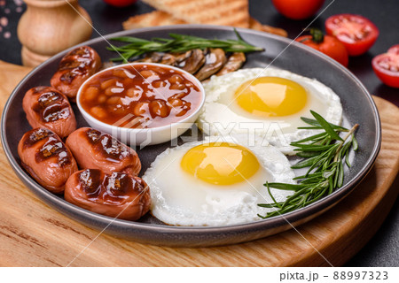 Full english breakfast with bean, fried eggs, roasted sausages, tomatoes and mushrooms Full english breakfast with bean, fried eggs, roasted sausages, tomatoes and mushrooms 88997323