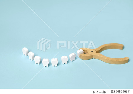 Tooth extraction with a dental instrument with forceps.  A model of teeth in the shape of a smile. Problems with wisdom teeth, toothache 88999967