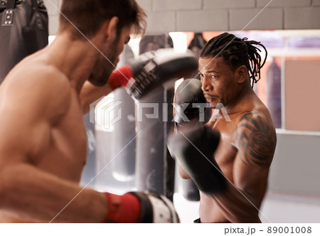Dedicated boxing partners. Shot of a young boxer practicing his punching with a partner. Dedicated boxing partners. Shot of a young boxer practicing his punching with a partner. 89001008
