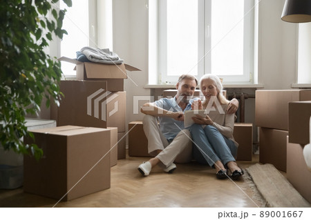 Mature spouses sit near boxes use tablet buy furniture 89001667