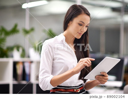 Working is easy when my office is in my hand. Cropped shot of an attractive young woman using a digital tablet in the office. 89002104