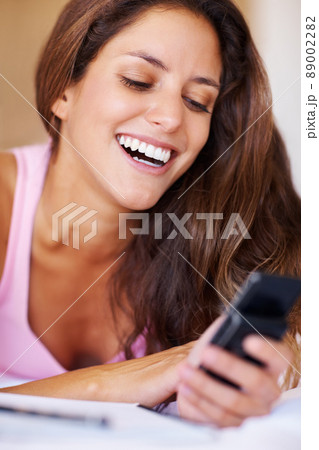 Pretty woman reading a funny text message. Pretty young woman taking a break from study and reading a funny text message. 89002282