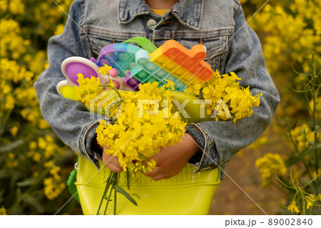 A girl in a rapeseed field with a backpack filled with modern educational popit and simple dimple toys. A bouquet of rapeseed flowers in the hands of a child. Toys made of plastic 89002840