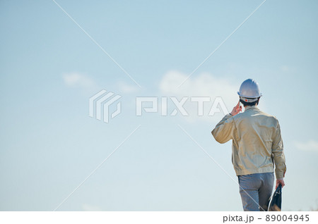 青空を背景にスマホで会話をする作業服姿の若い男性 青空を背景にスマホで会話をする作業服姿の若い男性 89004945