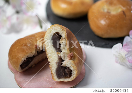 桜の塩漬けを真ん中にのせた二つに割られた美味しそうな桜あんパンのクローズアップ 89006452