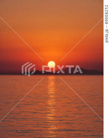 瀬戸内海の島陰に沈む夕日、縦構図 89008252