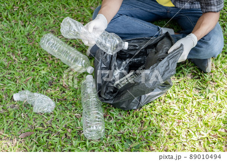 Man's hands pick up plastic bottles, put garbage in black garbage bags to clean up at parks, avoid pollution, be friendly to the environment and ecosystem 89010494
