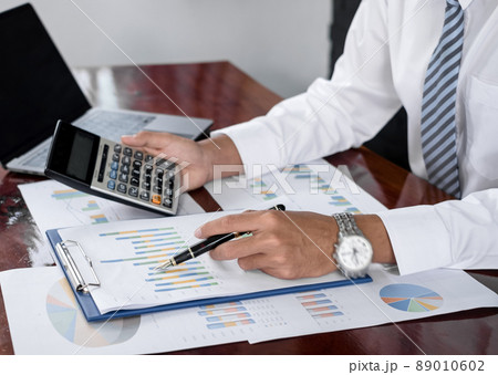 The businessman hand sits at their desks and calculates financial graphs showing the results of their investments planning the process of successful business growth The businessman hand sits at their desks and calculates financial graphs showing the results of their investments planning the process of successful business growth 89010602