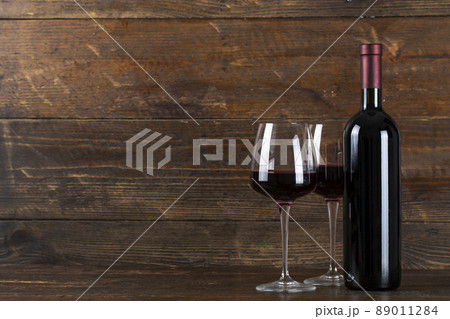 Wine bottle and two glasses on a wooden background. 89011284