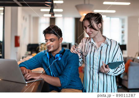 Multiethnic business people man with a female colleague working together on tablet and laptop computer in relaxation area of modern startup office 89011287