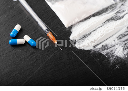Cocaine or other illegal drugs, white powder, money, pills, syringe on black background. Cocaine or other illegal drugs, white powder, money, pills, syringe on black background. 89011356