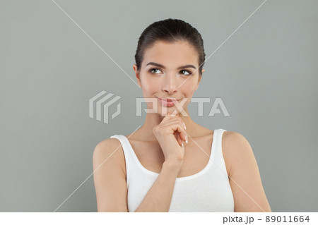 Beautiful young pretty thinking thoughtful woman posing on grey background. Beautiful young pretty thinking thoughtful woman posing on grey background. 89011664