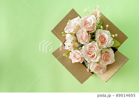 A beautiful blooming bouquet of pink roses in a parcel delivery cardboard box and copy space. Gift and love holiday concept and logistics service. A beautiful blooming bouquet of pink roses in a parcel delivery cardboard box and copy space. Gift and love holiday concept and logistics service. 89014605