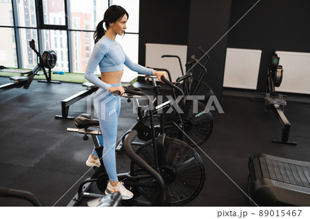 Sportswoman training on exercise bike in gym 89015467