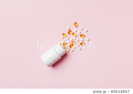 Multicolored pills and capsules in plastic bottle on Colored background, copy space. Many different various medicine tablets and pills, vitamin and nutritional supplements concept 89018807