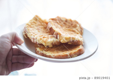 Close-up of a hand holding a plate of fried egg sandwiches in a white plate. The concept of a quick breakfast. High quality photo 89019401