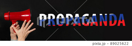 Female hand holding loudspeaker on black background. Russian propaganda and fake news concept Female hand holding loudspeaker on black background. Russian propaganda and fake news concept 89025622