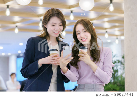 スマホを見ながら打ち合わせする若い女性 89027441