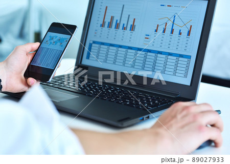 Businessman using smart phone and laptop with stock data on screen. 89027933