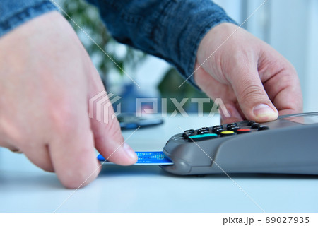 Hand dials pin code on pos terminal with credit card. 89027935