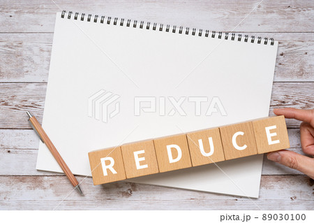 「REDUCE」と書かれた積み木、ノート、ペン、手 89030100
