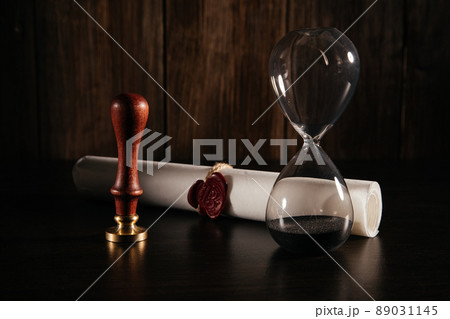 Old notarial wax seal on tied scroll and hourglass in lawyer office Old notarial wax seal on tied scroll and hourglass in lawyer office 89031145