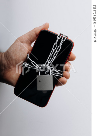 Modern smartphone with chain locked in man's hand. Social network issues and information security concept. Vertical image 89031283