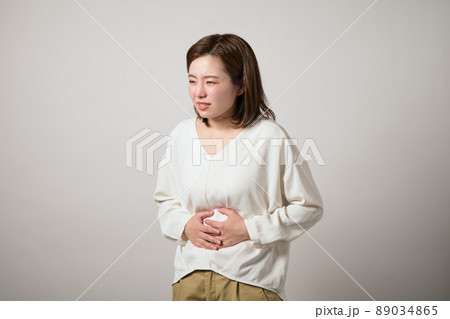 お腹が痛くて手でおさえる若い女性 お腹が痛くて手でおさえる若い女性 89034865