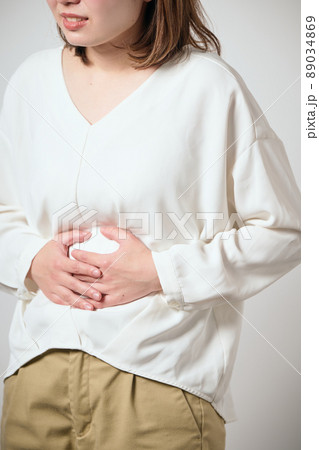 お腹が痛くて手でおさえる若い女性 89034869