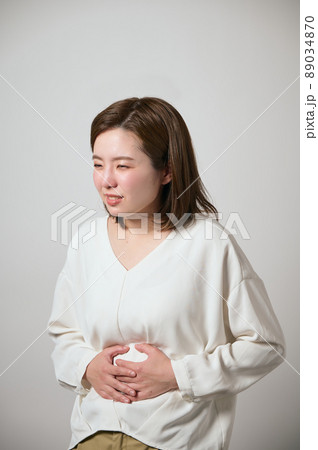 お腹が痛くて手でおさえる若い女性 89034870