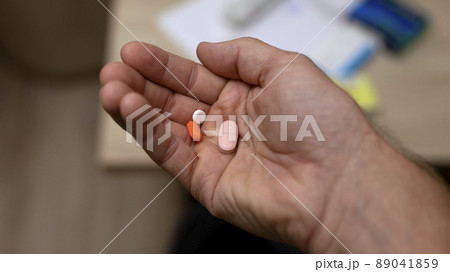 man's hand holding several pills in his hand 89041859