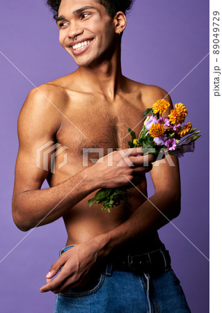Smiling athletic transgender man with flowers close-up portrait shot. Naked torso sportsman 89049729