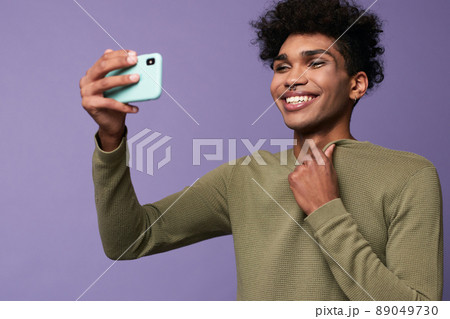 Portrait of transgender latino male taking selfies with mobile in hand. Happy trans gender young man Portrait of transgender latino male taking selfies with mobile in hand. Happy trans gender young man 89049730