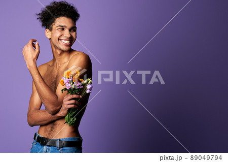 Smiling muscular transgender model with bouquet portrait. Nude torso young man of trans gender 89049794