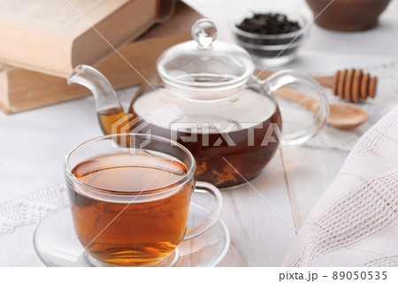 Glass cup of tea and teapot on white wooden table 89050535