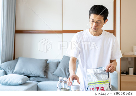 非常持ち出し袋に非常食などをパッキングしている男性 89050938