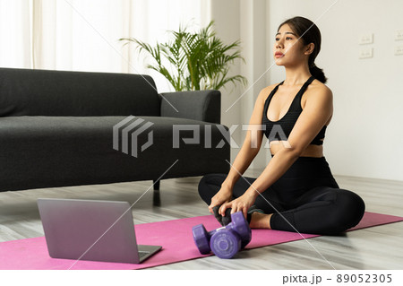 Beautiful young asian woman practicing yoga watching videos on laptop at home - Fitness, workout concept Beautiful young asian woman practicing yoga watching videos on laptop at home - Fitness, workout concept 89052305
