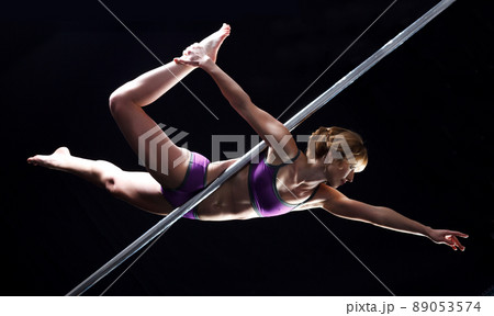 The strong and graceful young girl performing acrobatic exercises on pylon The strong and graceful young girl performing acrobatic exercises on pylon 89053574