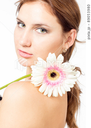 Portrait of beautiful woman with bright make up holding pink daisy in hands Portrait of beautiful woman with bright make up holding pink daisy in hands 89053980