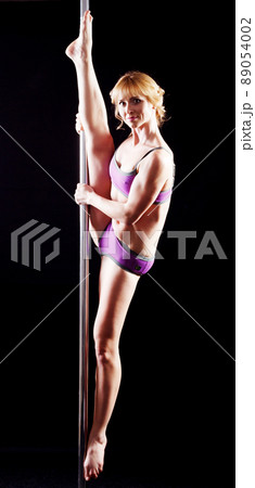 The strong and graceful young girl performing acrobatic exercises on pylon 89054002