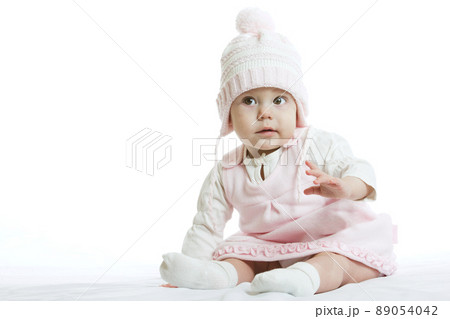 Little baby in knit winter clothing closing face with knitted beanie on the bed in the blue bedroom, New family and baby protection concept 89054042