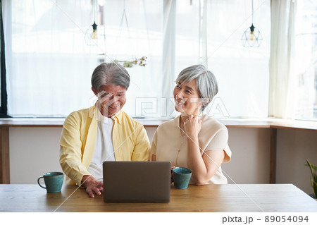 ノートパソコンを見ながら会話をする夫婦 ノートパソコンを見ながら会話をする夫婦 89054094
