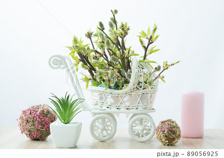 Home decoration. Branches of different trees grow from a toy stroller. Stylish and unusual decor for Easter. Jewelry with a hint of pregnancy. Mothers Day 89056925