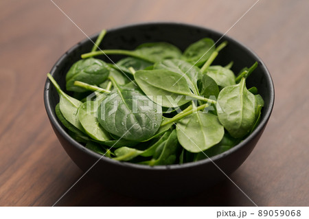 Fresh spinach leaves in black bowl on walnut wood table Fresh spinach leaves in black bowl on walnut wood table 89059068