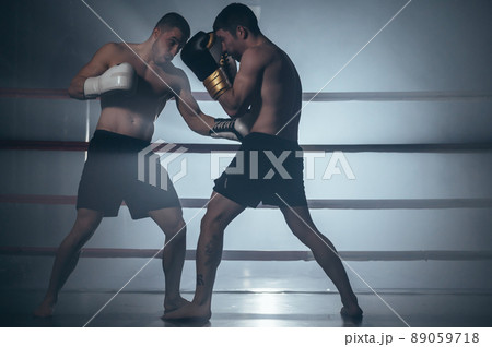 Two shirtless muscular man fighting Kick boxing combat in boxing ring. 89059718