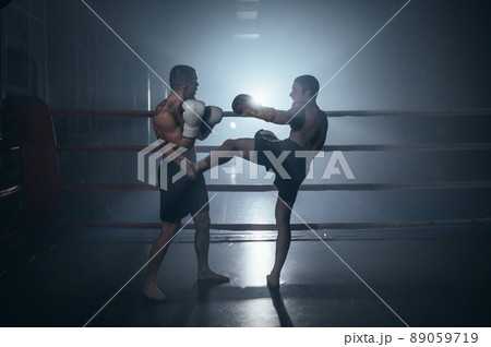 Two shirtless muscular man fighting Kick boxing combat in boxing ring. 89059719