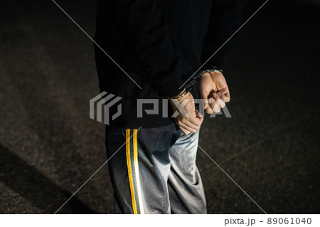 後ろ手に手錠をされる男性の腕 89061040
