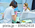 Woman dentist with assistant prepares patient for teeth whitening procedure. 89062418